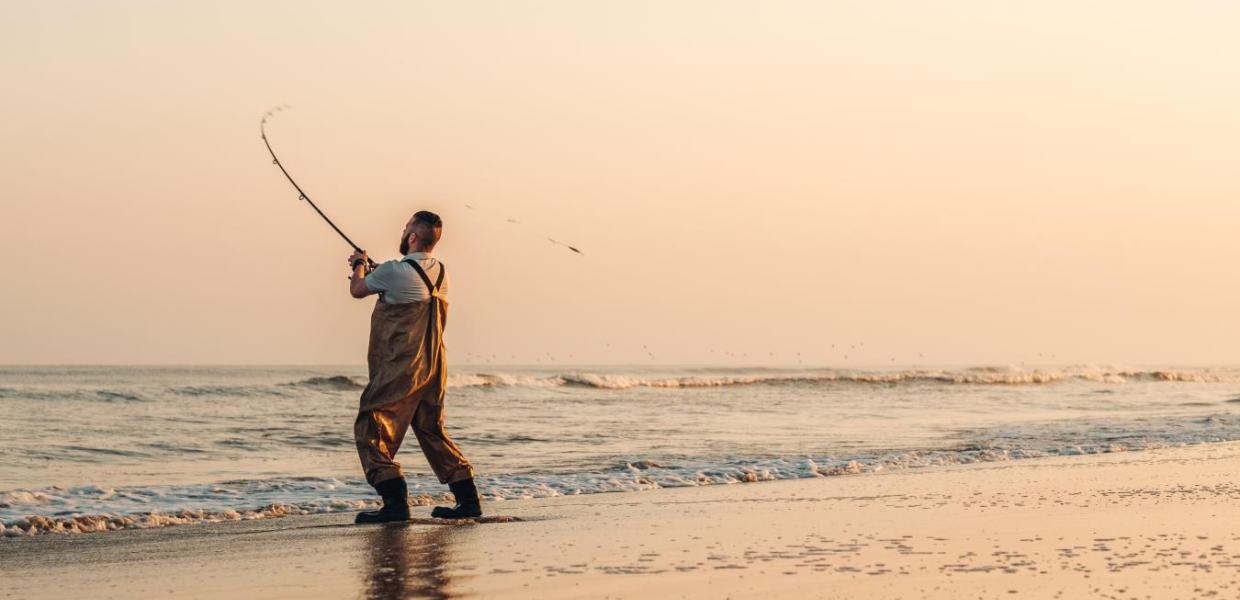 Mand som fisker på stranden